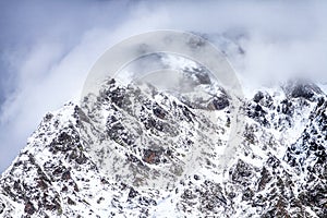 Beautiful dramatic snowy Caucasus mountain peaks in clouds. Scenic winter landscape