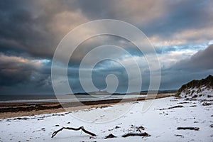 Beautiful dramatic unusual Winter landscape of snow on Embleton Bay beach in Northumberland England