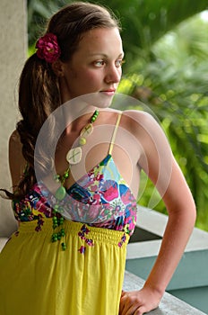 Beautiful dreaming girl on the balcony in a yellow sundress