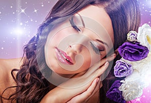 Beautiful dreamy woman with eyes closed, beside purple flowers