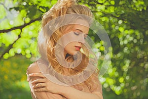 Beautiful dreamy young woman relaxing in the shade of the trees on a warm summer day