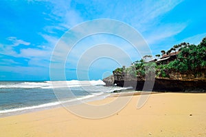 Beautiful drini beach in yogyakarta with bright blue sky, white sand and high cliffs.