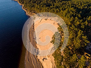 Beautiful drone areal photography view of large dune and pine forest near river Lielupe. Photo taken on sunset