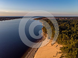 Beautiful drone areal photography view of large dune and pine forest near river Lielupe. Photo taken on sunset