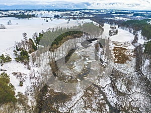 Beautiful drone winter landscape of Poland - snowy fields, lake, river and forest aerial view