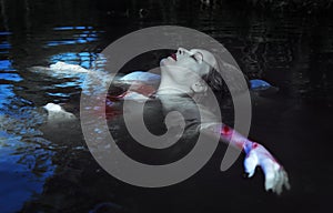 Beautiful drowned woman in bloody dress lying in the water