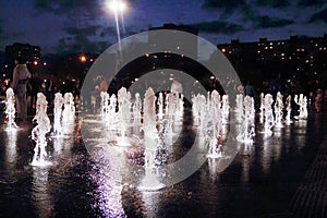 Beautiful dry fountain with white illuminated jets at dark night