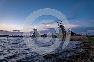 Beautiful Dutch landscape of Zaanse Schans village. Ancient windmills at the water's edge against a blue sky at dusk