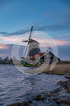 Beautiful Dutch landscape of Zaanse Schans village. Ancient windmills at the water's edge against a blue sky at dusk