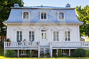 Patrimonial white house with Mansard metal roof and decorative wooden details