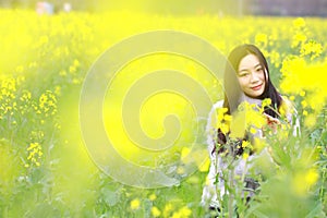 At beautiful early spring, a young woman stand in the middle of yellow flowers filed which is the biggest in Shanghai