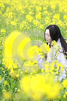 At beautiful early spring, a young woman stand in the middle of yellow flowers filed which is the biggest in Shanghai