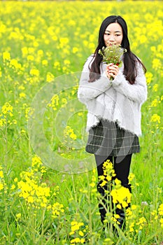 At beautiful early spring, a young woman stand in the middle of yellow flowers filed which is the biggest in Shanghai