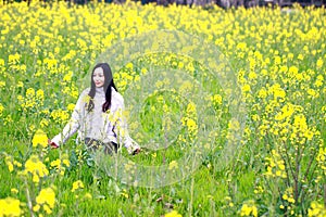 At beautiful early spring, a young woman stand in the middle of yellow flowers filed which is the biggest in Shanghai