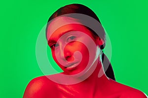 Beautiful east woman close up portrait isolated on green background in red neon light