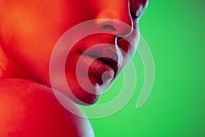 Beautiful east woman close up portrait isolated on green background in red neon light