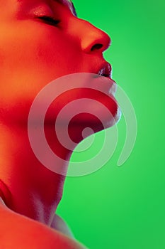 Beautiful east woman close up portrait isolated on green background in red neon light