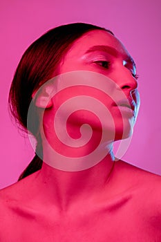 Beautiful east woman portrait isolated on pink studio background in neon light, monochrome