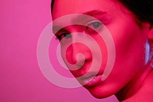 Beautiful east woman portrait isolated on pink studio background in neon light, monochrome