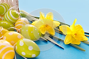 Beautiful Easter card with colorful eggs and  yellow daffodils on paper blue background