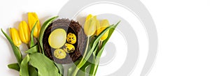 Beautiful Easter composition with yellow eggs in the nest and spring flowers on a white background. Banner. Copy space, top view