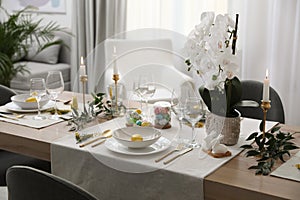Beautiful Easter table setting with white orchid flowers indoors