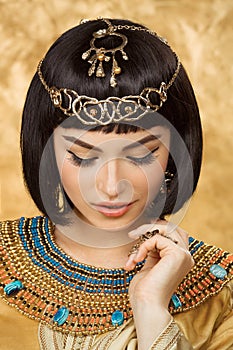 Beautiful Egyptian woman like Cleopatra on golden background