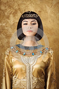 Beautiful Egyptian woman like Cleopatra on golden background