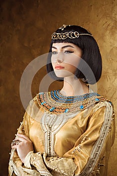 Beautiful Egyptian woman like Cleopatra on golden background