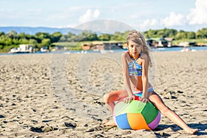 Beautiful eight year old girl playing with the ball on the beach