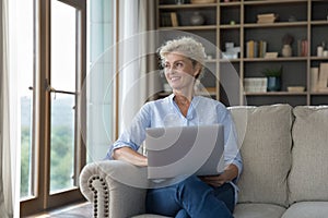 Beautiful elderly blond woman spends free time using laptop