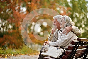 Beautiful elderly couple sitting together on a bench in autumn