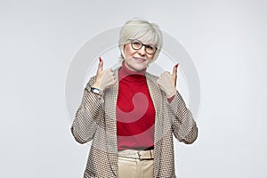 beautiful elderly woman with glasses gives a thumbs up. the concept of a business woman leader