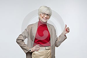 beautiful elderly woman with glasses gives a thumbs up. the concept of a business woman leader