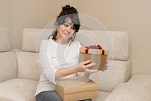 beautiful elderly woman holding gifts in her hands with a very surprised and joyful expression
