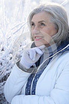 Beautiful elderly woman posing in a snowy winter park