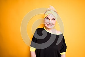 Beautiful elderly woman in a sports bandage on her head and in a black T-shirt smiling and getting ready for a workout