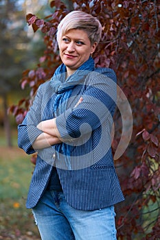 Beautiful elegant blond woman posing in autumn city park, dressed in blue jeans and jacket