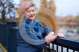 Beautiful elegant blond woman posing in autumn city park, dressed in blue jeans and jacket