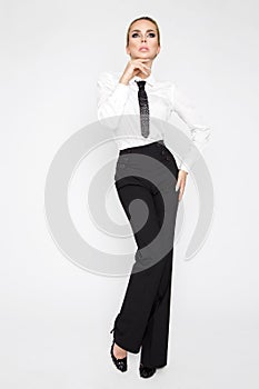 Beautiful, elegant, blonde female model dressed in white shirts and tie and black pants.