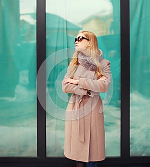 Beautiful elegant blonde woman wearing a coat jacket and sunglasses in city