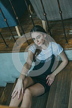 Beautiful elegant brunette girl wearing a black dress is relaxing in a street cafe. Advertising, fashion. Tinted photo