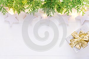 Beautiful elegant Christmas New Year background. White stars sparkling golden lights garland green juniper gift box on plank wood