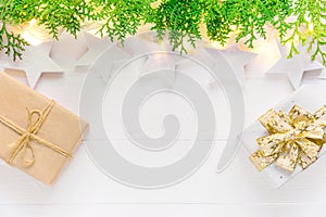Beautiful elegant Christmas New Year background. White stars sparkling golden lights garland green juniper gift boxes on wood