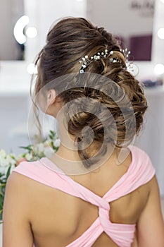 Beautiful elegant evening hairstyle on dark hair beautiful girl with an ornament from stones in her hair, hairstyle for the