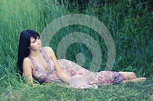 Beautiful elegant girl lying in high grass in summer