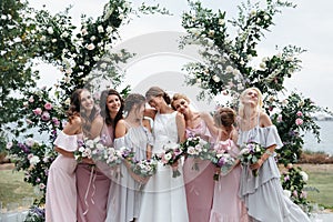 Beautiful elegant slim smiling bridesmaids in delicate pink beige summer dress on the wedding ceremony.