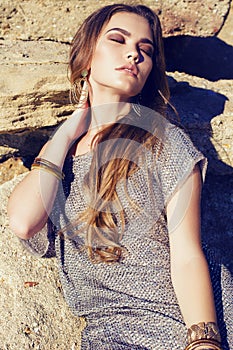 beautiful elegant woman with long hair dressed in posing on the rocks