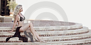 Beautiful elegant woman model in black bikini posing on staircas