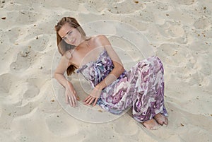 Beautiful elegant woman sit on sand